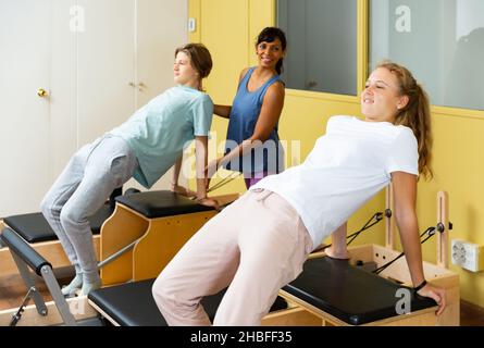 Adolescents d'entraînement pilates dans la salle de gym avec entraîneur Banque D'Images