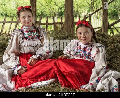 Salaj, Roumanie - 15 mai 2018 : jeunes filles rurales vêtues de costumes traditionnels assis dans un hanyloft lors de la récolte à la campagne Banque D'Images