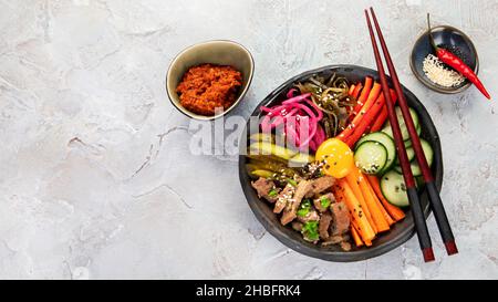 Bibimbap avec en-cas sur fond gris.Cuisine traditionnelle coréenne.Vue de dessus, plat, espace de copie Banque D'Images