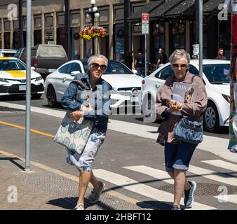 Deux femmes actives et stylées qui marchent sur un zèbre dans le centre-ville de Victoria en Colombie-Britannique.Femmes âgées traversant la rue. Banque D'Images