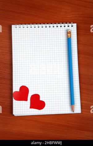 Bloc d'écriture vierge avec formes en forme de coeur et crayon sur la table Banque D'Images