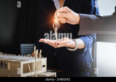 Les agents donnent les clés de la maison du client au bureau de l'agence.Accord et concept immobilier. Banque D'Images