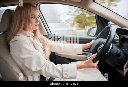 Belle jeune femme au volant d'une voiture moderne.Vue de l'intérieur d'une voiture.Conducteur blond portant des vêtements décontractés. Banque D'Images