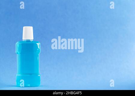 Flacon de rince-bouche pour une hygiène bucco-dentaire de routine sur fond bleu clair. Banque D'Images