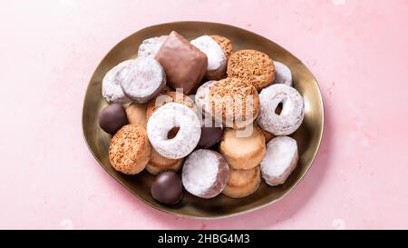 Spécialités de vacances polvorones et mantecados dans assiette dorée sur table rose, vue de dessus Banque D'Images