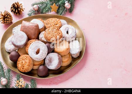 Les délices des fêtes polvorones et les mantecados en assiette dorée sur table rose décorée de boules dorées, branches d'arbre de noël et cônes de pin, haut Banque D'Images