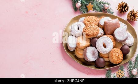 Les délices des fêtes polvorones et les mantecados en assiette dorée sur table rose décorée de boules dorées, branches d'arbre de noël et cônes de pin, haut Banque D'Images