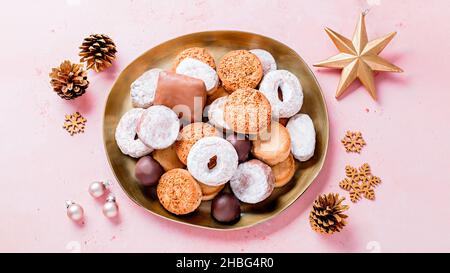 Spécialités de vacances polvorones et mantecados en assiette dorée sur table rose décorée de boules dorées et de cônes de pin, vue de dessus Banque D'Images