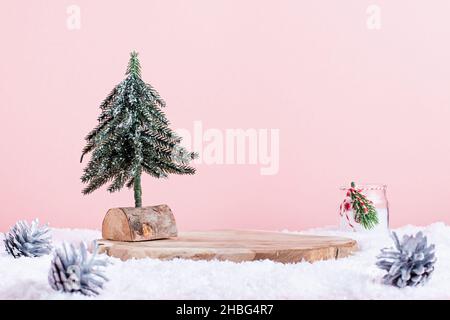 Podium en bois ou support avec un arbre de Noël minimal et bougie dans la neige sur fond rose pastel.Vide support en bois pour présenter le produit avec Noël Banque D'Images