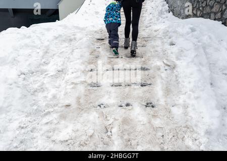 Les gens marchent à côté d'un escalier en pierre de béton couvert de neige profonde et sale après une tempête de neige blizzard sur la passerelle piétonne de la ville.Chute de la lame Banque D'Images