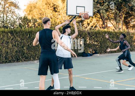 Homme passant une balle pendant un match de basket-ball entre amis sur un terrain de plein air Banque D'Images