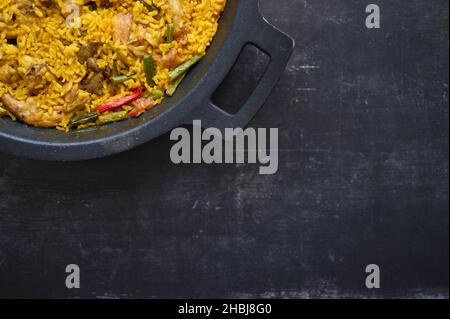 détail d'une paella de riz et de lapin avec poivrons sur fond noir Banque D'Images