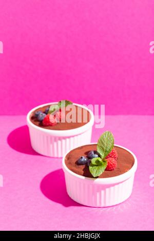 Parfait gâteau tiramisu maison à la menthe fraîche.Portion tiramisu en plaque blanche sur fond rose ombres dures. Banque D'Images