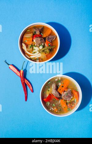 Soupe traditionnelle asiatique, ouzbek, Moyen-Orient avec bœuf ou agneau et légumes.Shorpa, sherpa, chorba sur bleu Banque D'Images