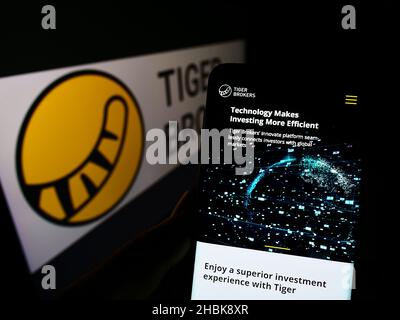 Personne tenant smartphone avec la page web de la société FINTECH Holding Limited (Tiger Brokers) à l'écran avec logo.Concentrez-vous sur le centre de l'écran du téléphone. Banque D'Images