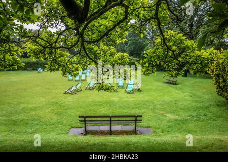 Bletchley Park Mansion, donnant sur le jardin luxuriant, un banc et des chaises longues en arrière-plan une voûte d'arbres en premier plan, 11 06 2021 Banque D'Images