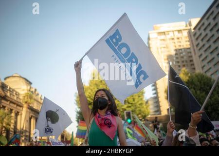 Santiago, Chili.19th décembre 2021.Une femme signe un drapeau en faveur de Gabriel Boric pendant la célébration.le candidat de Apruebo Dignidad pacte gagne l'élection présidentielle de 2021 au Chili, avec plus de la moitié des voix contre le candidat de l'extrême droite radicale Jose Antonio Kast.Crédit : SOPA Images Limited/Alamy Live News Banque D'Images