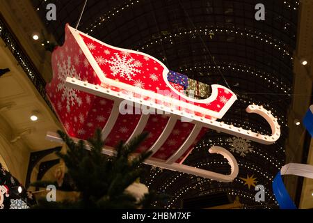 Traîneau rouge vif du père noël avec boîtes cadeaux et flocons de neige dans le centre commercial le soir du nouvel an.Gros plan Banque D'Images