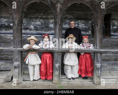 Salaj, Roumanie-15 mai 2018 : enfants portant des costumes roumains traditionnels devant une ancienne église en bois dans la région de Transylvanie, Roumanie. Banque D'Images