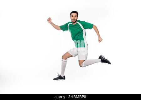 joyeux jeune joueur de football en uniforme sautant isolé sur blanc Banque D'Images
