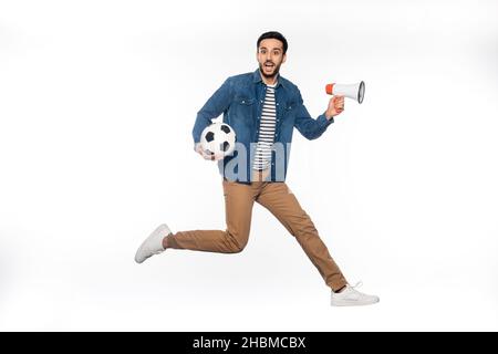 un homme heureux qui fait le jeu tout en tenant le ballon de football et le haut-parleur sur du blanc Banque D'Images