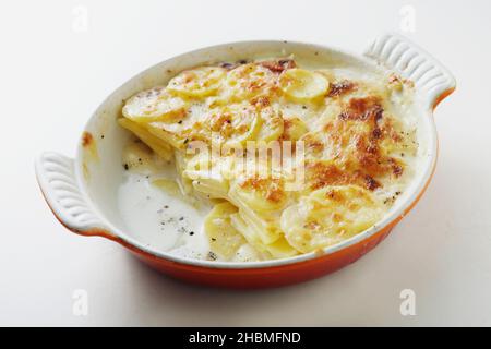 De dessus de délicieux gratin de dinis de dinis fait de tranches de pommes de terre cuite dans la crème dans une casserole de céramique et servi sur table blanche Banque D'Images