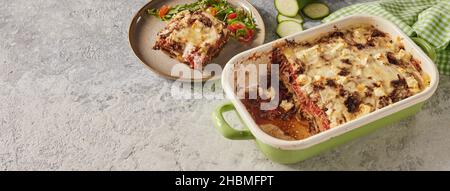 De dessus de savoureux moussaka grec traditionnel avec viande hachée et aubergines en couches dans une casserole avec fromage et sauce et servi dans table grise Banque D'Images