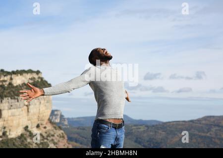 Homme excité à la peau noire célébrant des vacances dans la montagne des bras s'étirant Banque D'Images