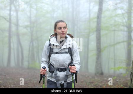 Vue de face d'une heureuse femme de trekker marchant dans une forêt en hiver Banque D'Images