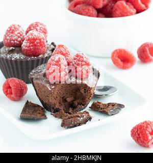 Gros plan des tasses de chocolat remplies de mousse au chocolat et recouvertes de framboises. Banque D'Images