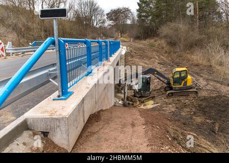 La pelle hydraulique ajuste le terrain autour du nouveau pont.Achèvement des travaux de construction d'un pont sur une route de campagne en République tchèque. Banque D'Images