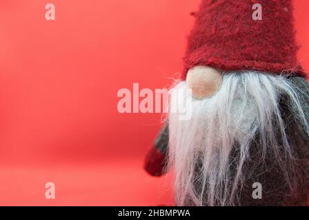 Gnome de Noël ancien sur fond rouge avec espace libre pour le texte.Carte postale d'hiver avec Scandinavian Dwarf dans Red Hat. Banque D'Images