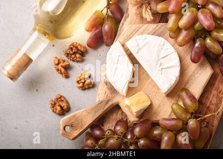 Deux bouteilles de vin avec raisins, fromage en tranches camembert, noix et lunettes de vin sur fond de table en béton gris avec espace de copie.Vin rouge avec une vigne Banque D'Images