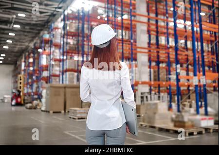 Femme avec ordinateur portable dans l'entrepôt avec dos à la caméra Banque D'Images