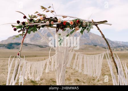 Arche de mariage décorée de macrame, de fleurs et de branches dans le champ Banque D'Images