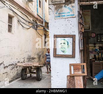 VILLE DE PIERRE, ZANZIBAR, TANZANIE - 13 MARS 2017 : rue étroite de la ville de pierre avec un jeune homme, une charrette en bois et une boutique de charpente Banque D'Images