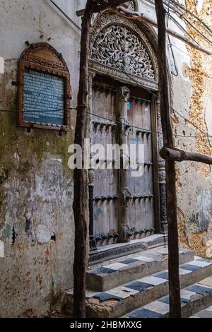 VILLE DE PIERRE, ZANZIBAR - 13 MARS 2017 : gros plan d'un marqueur historique et porte en bois sculptée avec soin à la demeure de Tippu Tip, un site classé au patrimoine mondial Banque D'Images