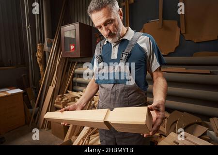 Maître barbu sérieux regardant la jambe de table Banque D'Images