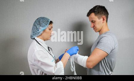 Le médecin de Brunette examine l'avant-bras cassé du jeune homme Banque D'Images