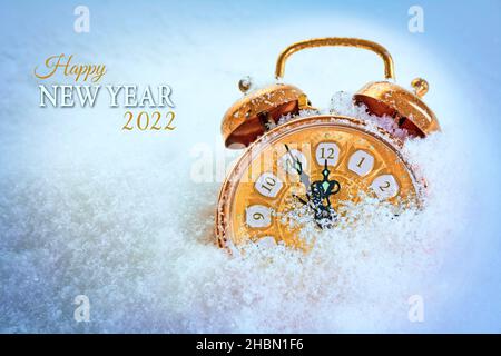 Radio-réveil vintage couleur cuivre dans la neige pointant cinq minutes avant douze, texte Happy New Year 2022, carte de vœux de saison avec espace pour les copies Banque D'Images