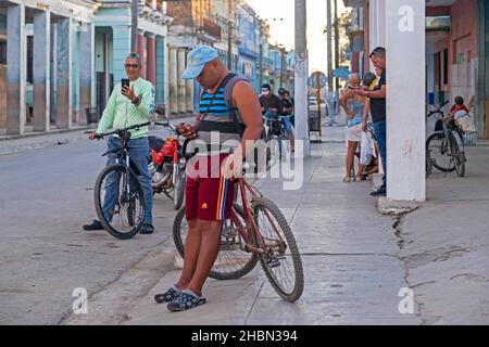 Groupe d'habitants cubains locaux essayant de connecter des smartphones à Internet via Wi-Fi dans les rues de Colón, province de Matanzas sur l'île de Cuba Banque D'Images