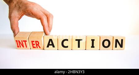 Symbole d'action ou d'interaction.Homme d'affaires tourne des cubes en bois et change le mot action en interaction.Beau tableau blanc fond blanc, copie Banque D'Images