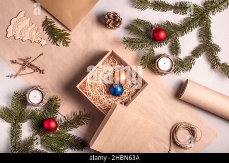 Emballage d'un cadeau de Noël et du nouvel an dans des matériaux écologiques : papier kraft, branches de sapin vivant, cône, ficelle.Étiquettes avec maquette, décor naturel Banque D'Images