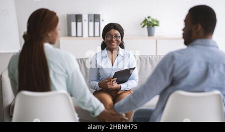 Couple millénaire tenant les mains après une psychothérapie efficace et une psychologue féminine positive au bureau Banque D'Images