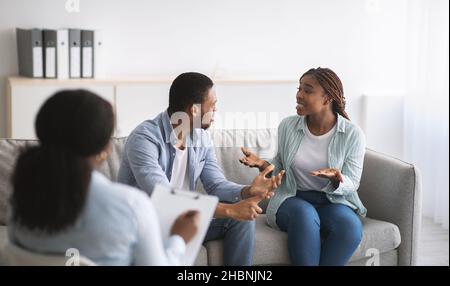 Jeune couple noir en conflit pendant la thérapie conjugale avec psychologue au bureau, panorama Banque D'Images