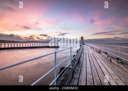 Coucher de soleil sur la jetée et le phare de Whitby West Banque D'Images