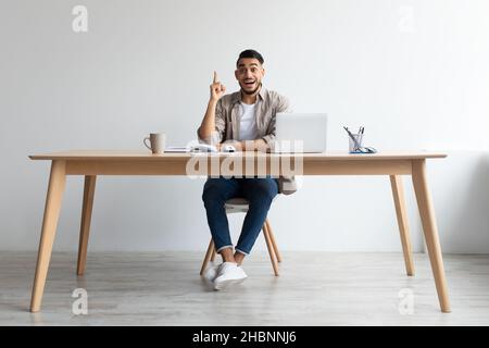 Concept d'idée.Un homme excité qui pointe le doigt vers le haut sur le lieu de travail Banque D'Images