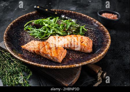 Dîner végétarien au barbecue - filets de saumon grillés steaks sur l'assiette avec salade.Arrière-plan noir.Vue de dessus Banque D'Images