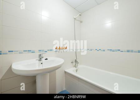 Toilettes avec lavabo blanc et baignoire et bordure en porcelaine bleue dans un appartement de location de vacances Banque D'Images