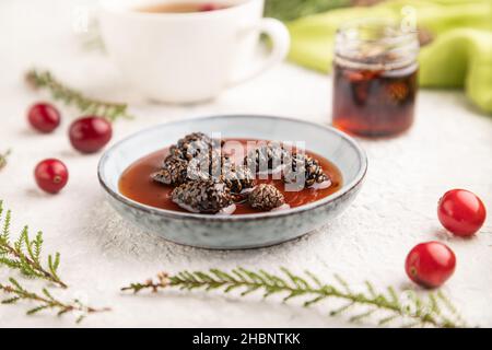 Confiture de cône de pin avec tisane sur fond de béton gris et textile de lin vert.Vue latérale, mise au point sélective. Banque D'Images